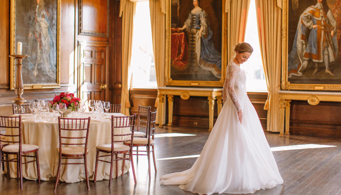 A bride in a flowing white gown stands amongst the opulent decoration and historic State Apartments at The Royal Hospital Chelsea