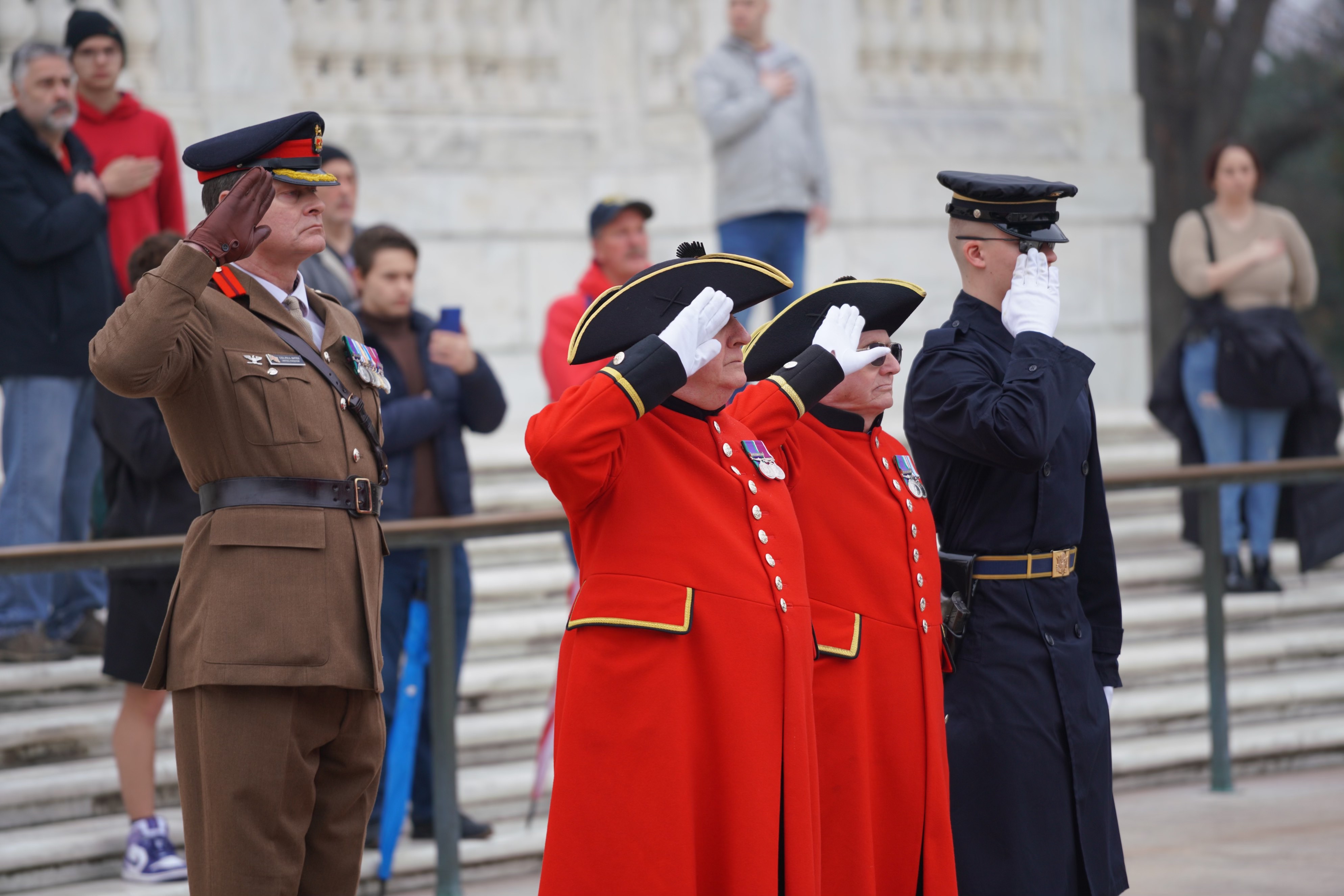 Chelsea Pensioners in scarlet uniforms saluting