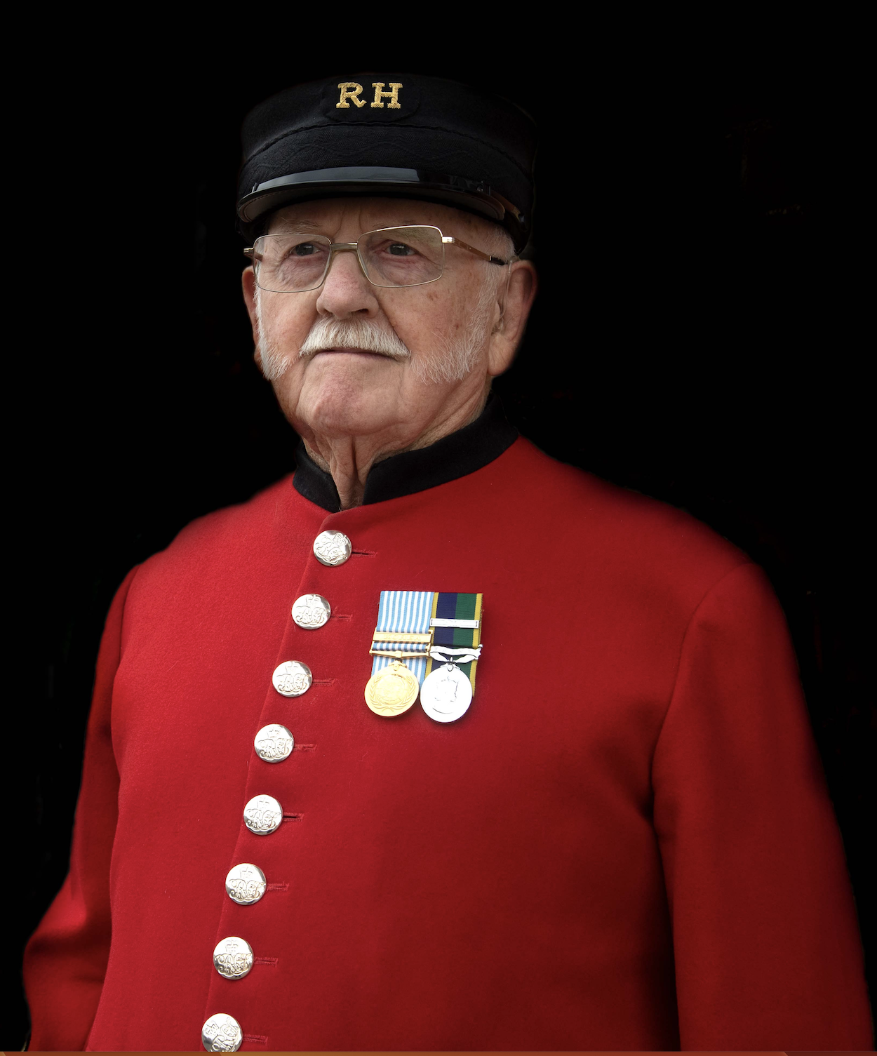 Chelsea Pensioner, George Reed, in his scarlet uniform in front of a black background