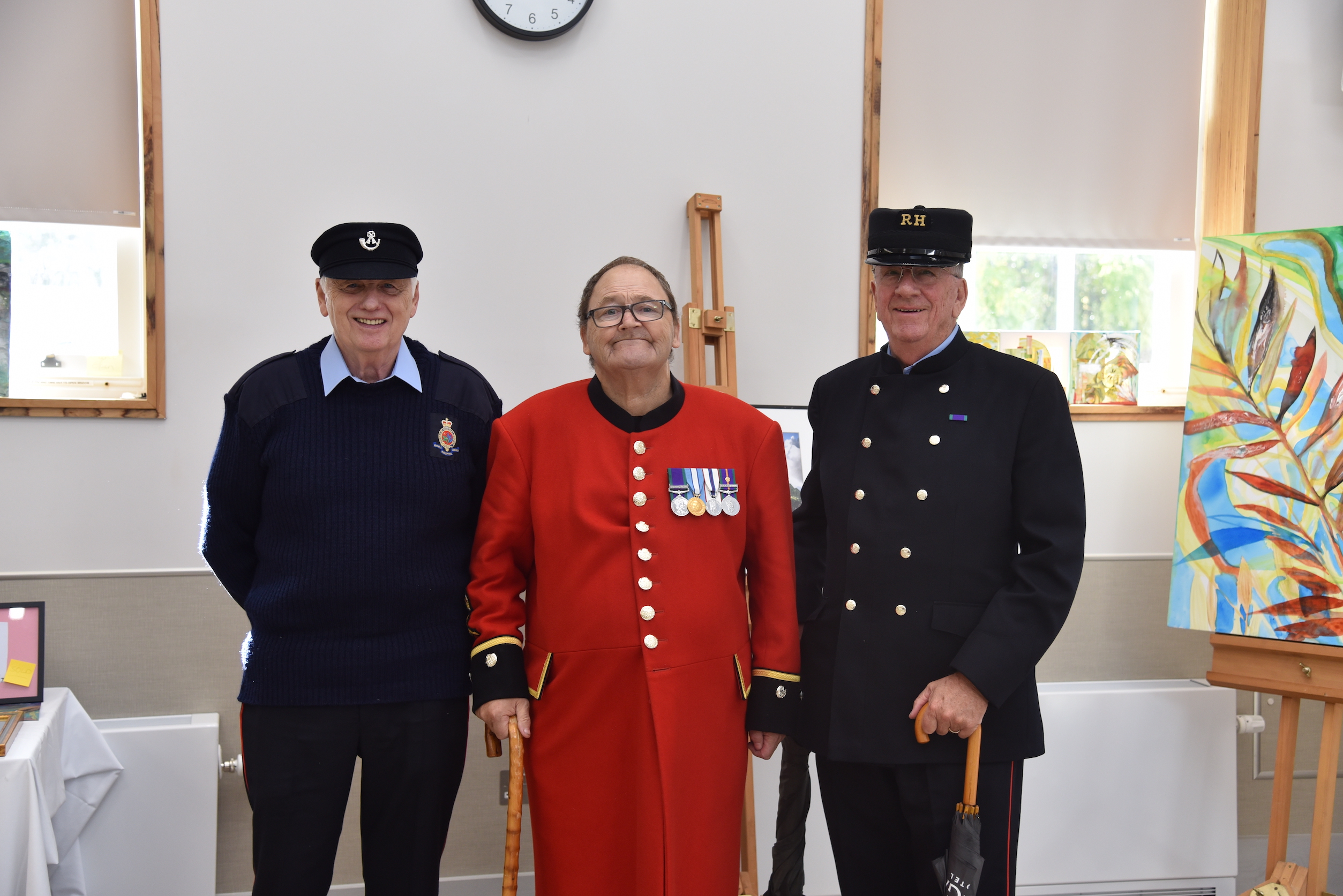 Three Chelsea Pensioners standing in front of painting at The Royal Hospital Chelsea art exhibition