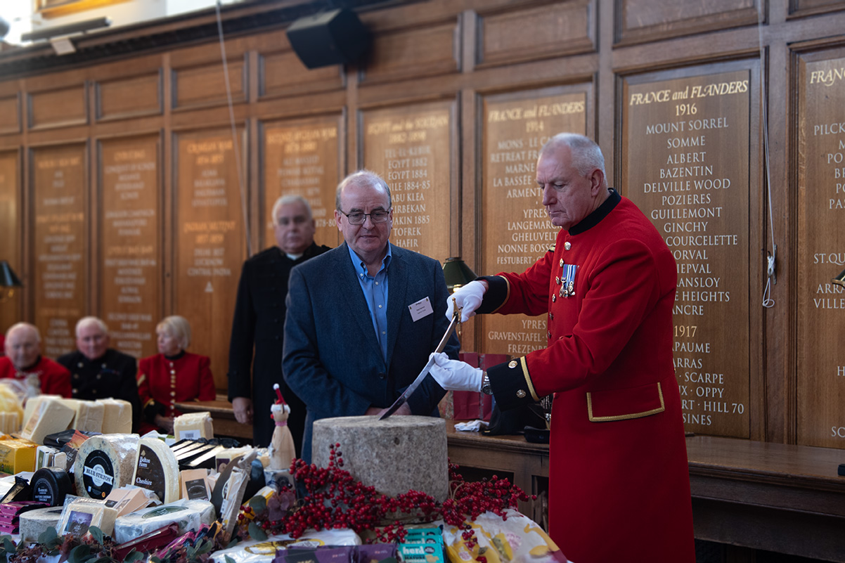 Chelsea Pensioner cuts the ceremonial cheese with a sword