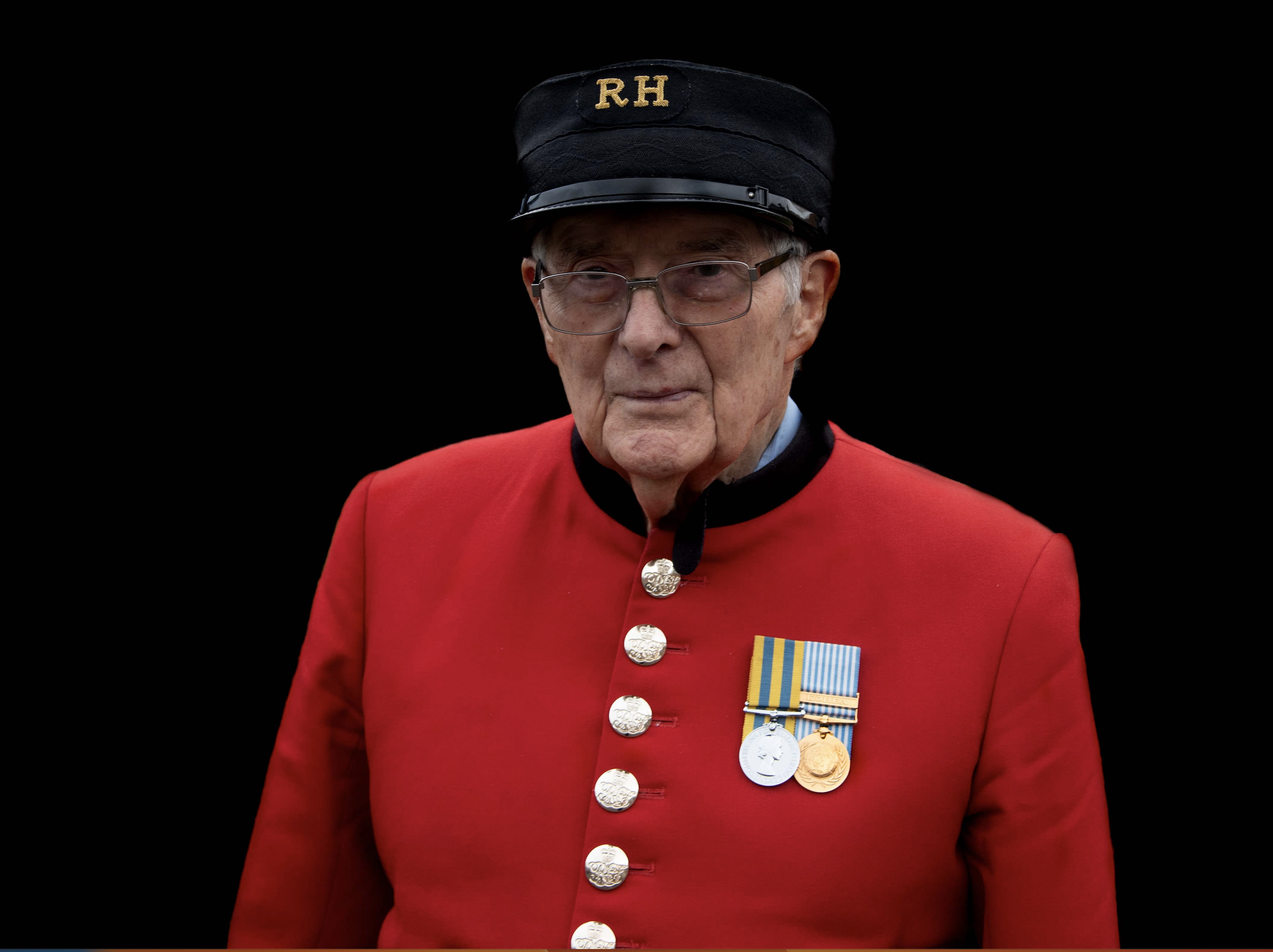 Chelsea Pensioner, Trevor John, in his scarlet uniform in front of a black background