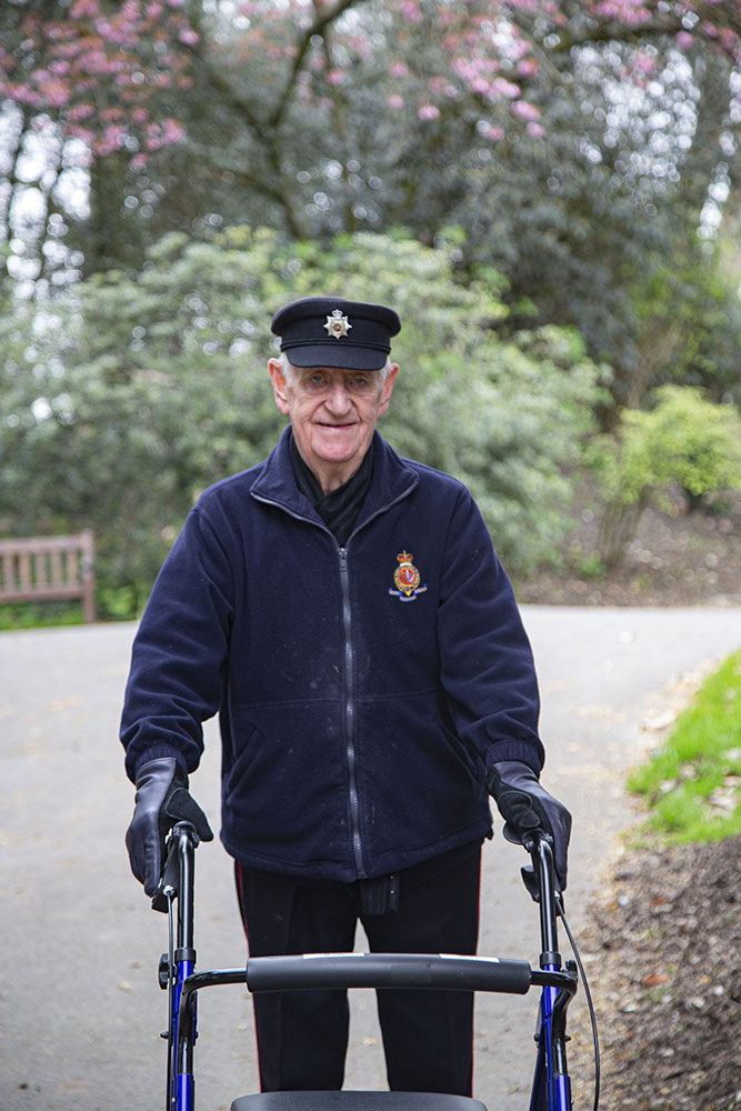 A Pensioner with a walking frame out walking in Ranelagh Gardens surrounded by trees on the walking path