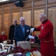 Chelsea Pensioner in scarlet uniform holding a sword to cut a 25kg Montgomery cheddar cheese