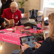 People sat round table looking at iPads. Pink House of Memories cloth in the middle with objects from the app on. 